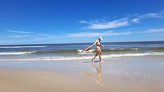 Amateur filming. A nudist plays with waves on the ocean shore.