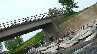 Blonde pissing outside in a river